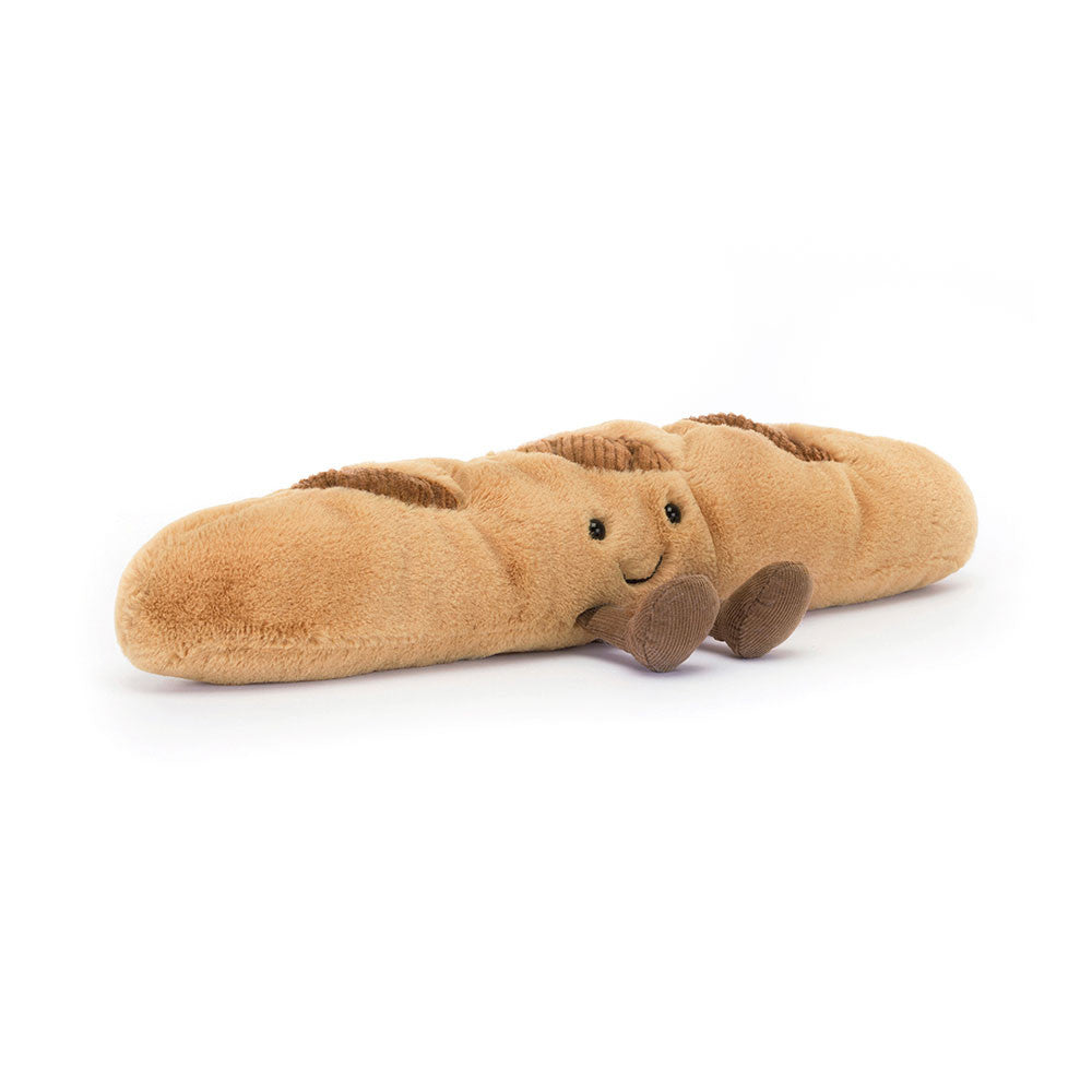 Plush toy by Jellycat of a long light brown smiling baguette with embroidered black eyes a happy smile small brown corduroy hands and feet and textured darker brown crust