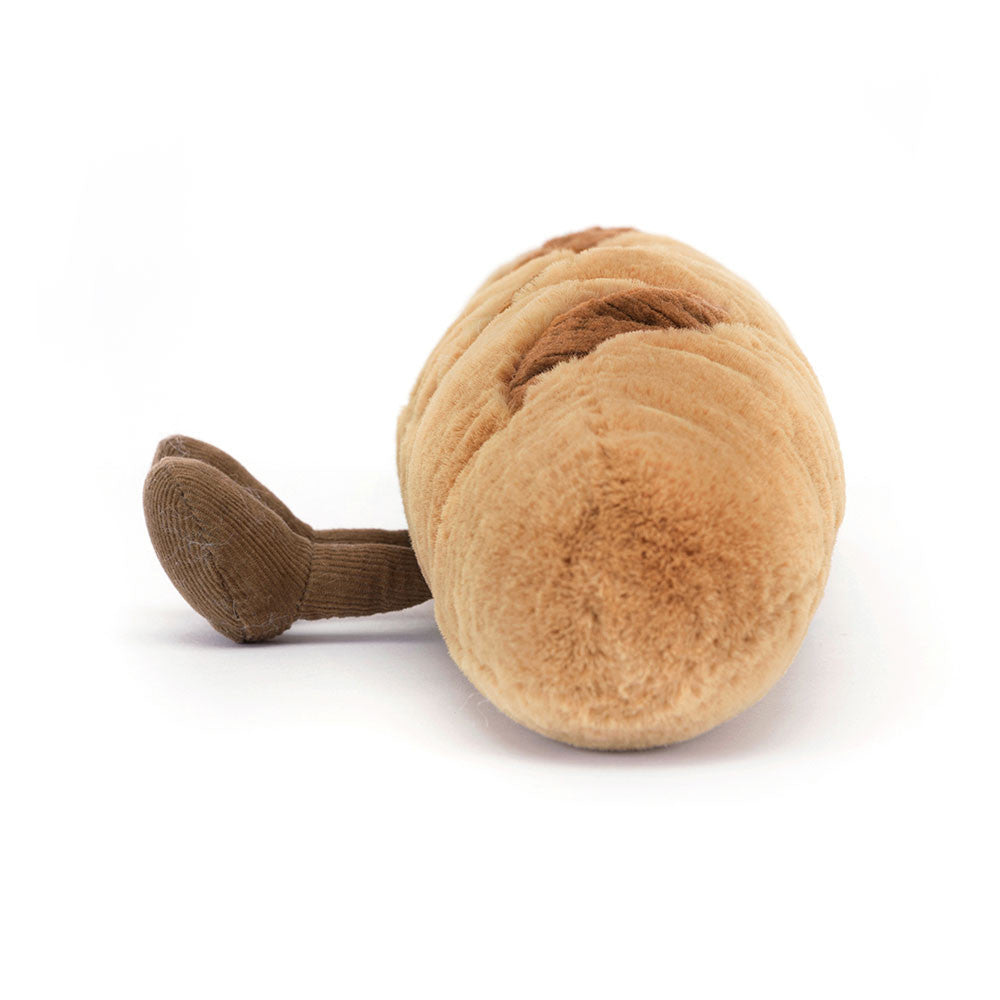 Plush toy baguette featuring fluffy light brown fabric with darker brown scoring lines and a small corduroy brown crust detail lying on a plain white background