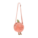 Jellycat plush crossbody bag shaped like a fuzzy light pink peach with a green leaf, cute embroidered smiling face, small brown feet, and an adjustable pink strap