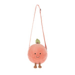 A fuzzy round peach-orange plush shoulder bag with a smiling embroidered face, a small green leaf, and tiny brown feet, suspended by a pink strap against a white background