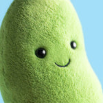 Close up of a green plush toy with black button eyes and a stitched smile