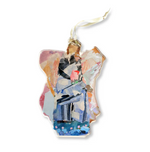 Acrylic on acrylic ornament by L. Dunn featuring an abstract angel with a gold-accented head, a blue and grey garment holding a red detail, and a vibrant mixed media background in pink, orange, and light blue hues, suspended by a white ribbon