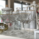 Group of textured glass martini glasses with gold rims on a white shelf