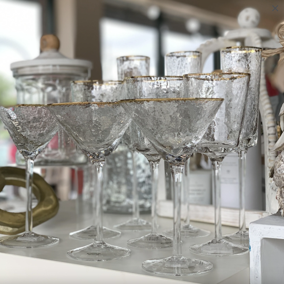 Group of textured glass martini glasses with gold rims on a white shelf