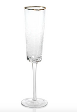 Tall clear glass champagne flute with a gold rim and textured surface