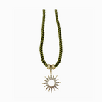 A vibrant olive green twisted cord necklace displaying two sparkling gold diamanté encrusted rings and an ornate sunburst pendant