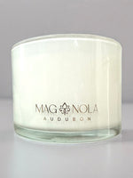 White candle in a glass jar with Magnolia Audubon label