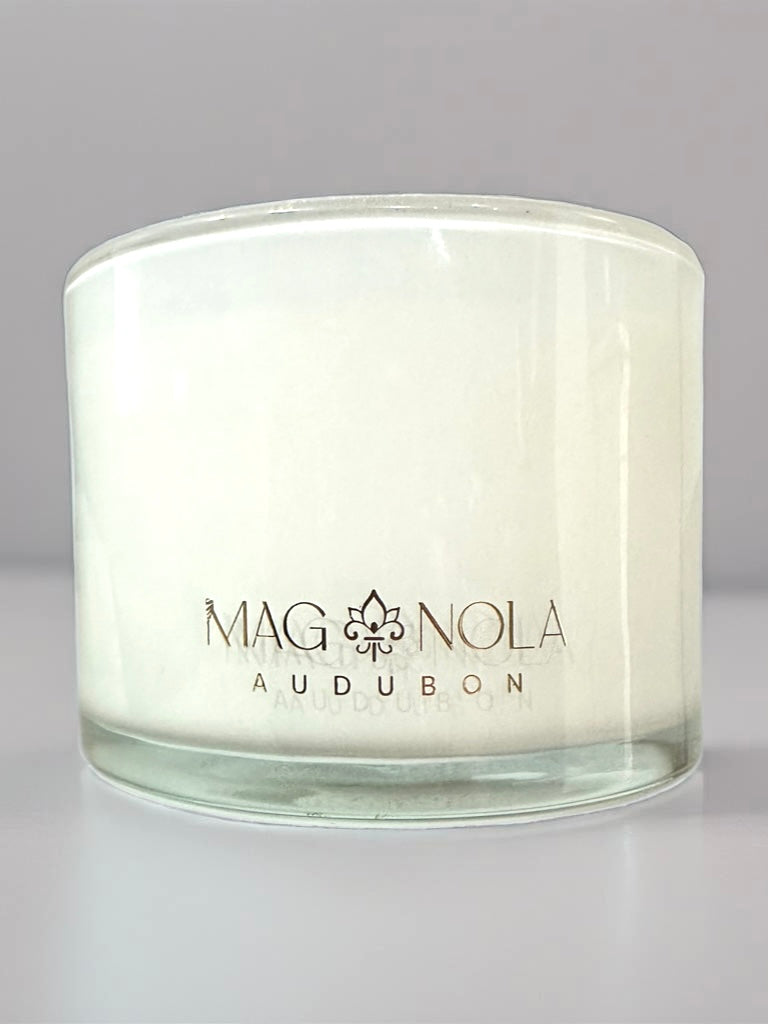 White candle in a glass jar with Magnolia Audubon label