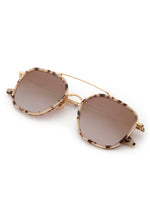 Product photo of stylish sunglasses featuring light tortoise shell geometric frames, brown gradient lenses, and a delicate gold metal double bridge on a clean white background