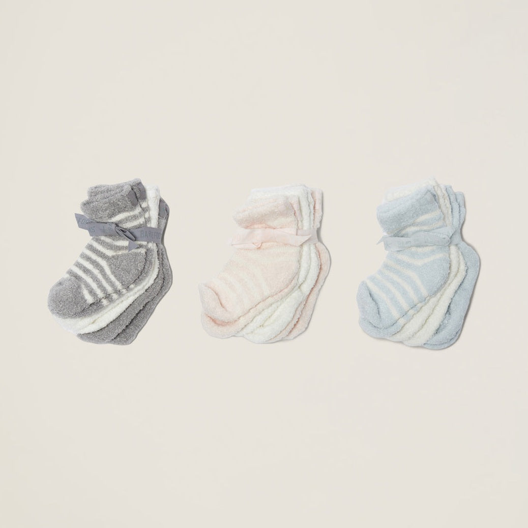 three sets of baby socks in grey and white stipe, pink and white stripe, and blue and white stripe on a taupe background