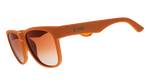 Goodr sunglasses with a matte orange frame and gradient brown to clear lenses featuring a gold goodr logo on the temple and a small yellow textured grip detail