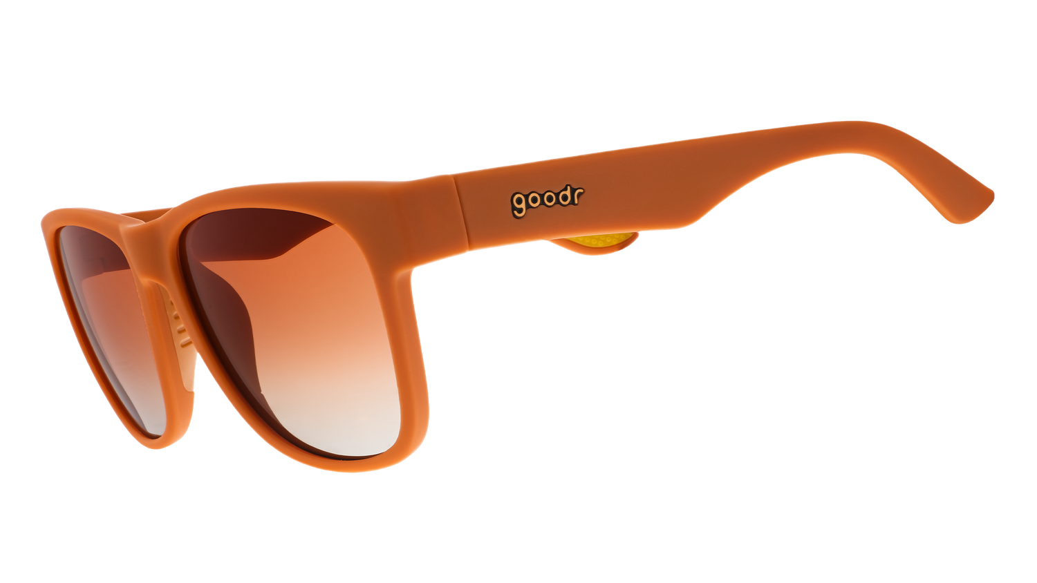Goodr sunglasses with a matte orange frame and gradient brown to clear lenses featuring a gold goodr logo on the temple and a small yellow textured grip detail