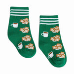 A pair of vibrant green socks with white cuff stripes featuring a repeating pattern of white coffee cups and plates piled high with powdered sugar beignets
