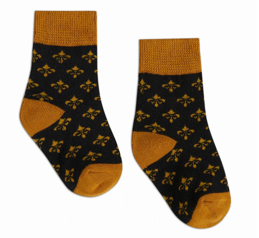 Textile pair of black socks featuring a repeating gold fleur-de-lis pattern with mustard yellow ribbed cuffs, heels, and toes