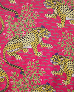 Illustrated textile pattern featuring dynamic yellow and black spotted leopards with blue accents on a vibrant hot pink background amidst green foliage and small pink berries
