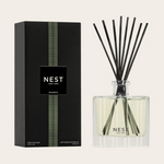 Product photography by NEST NEW YORK showcasing a Bamboo reed diffuser, featuring a sleek black box with a vibrant green vertical striped pattern and a clear square glass bottle holding light yellow liquid with elegant black reeds