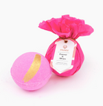 Two Musee bath bombs on a white background, one wrapped in fuchsia tissue with a 'Forever & Always' tag, the other unwrapped vibrant pink with a metallic gold stripe