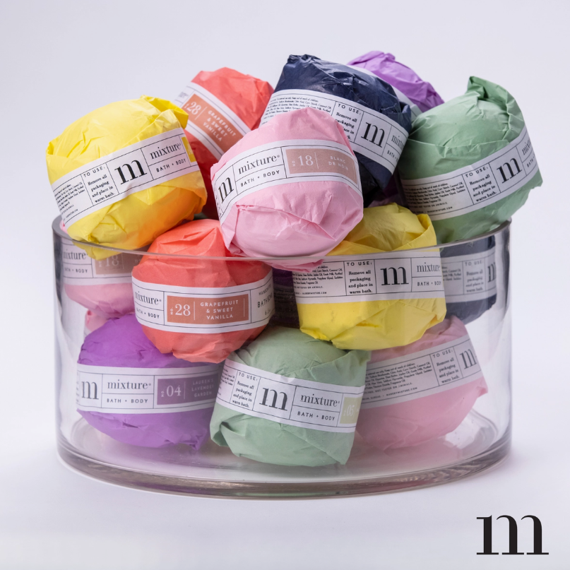 Glass bowl filled with assorted colorful wrapped bath bombs