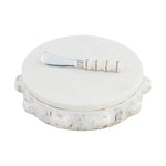 White marble pedestal server featuring a distressed white wooden base with carved round embellishments and a silver knife with a beaded wooden handle
