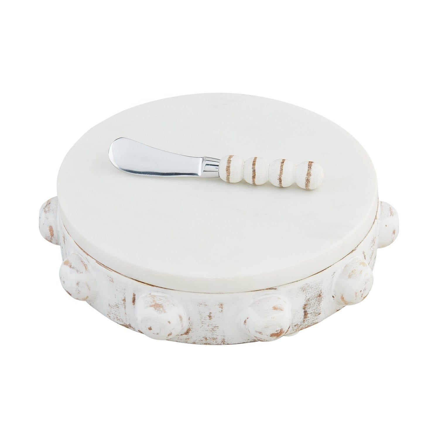 White marble pedestal server featuring a distressed white wooden base with carved round embellishments and a silver knife with a beaded wooden handle