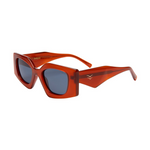 Product photography of I-SEA Birdie sunglasses featuring thick angular burnt orange frames, dark blue lenses, and a distinctive double-arrow temple logo on a white background