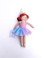 Plush doll Chloe the Birthday Bestie stands on a white background wearing a sparkly pink top a glittery blue and purple ombre tutu gold ballet slippers and a silver party hat atop her reddish-brown bun
