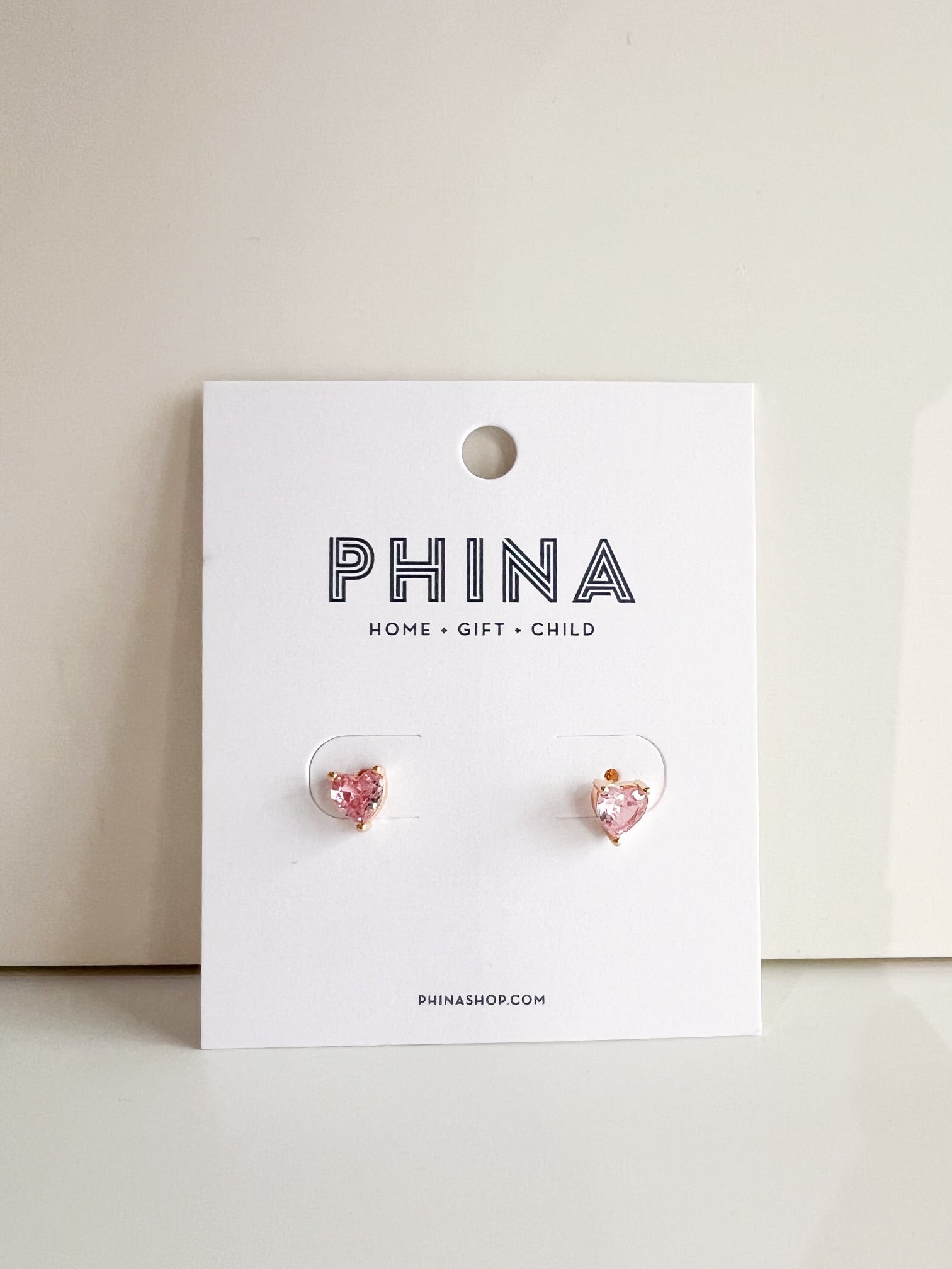 Pair of pink heart shaped stud earrings on a white branded display card