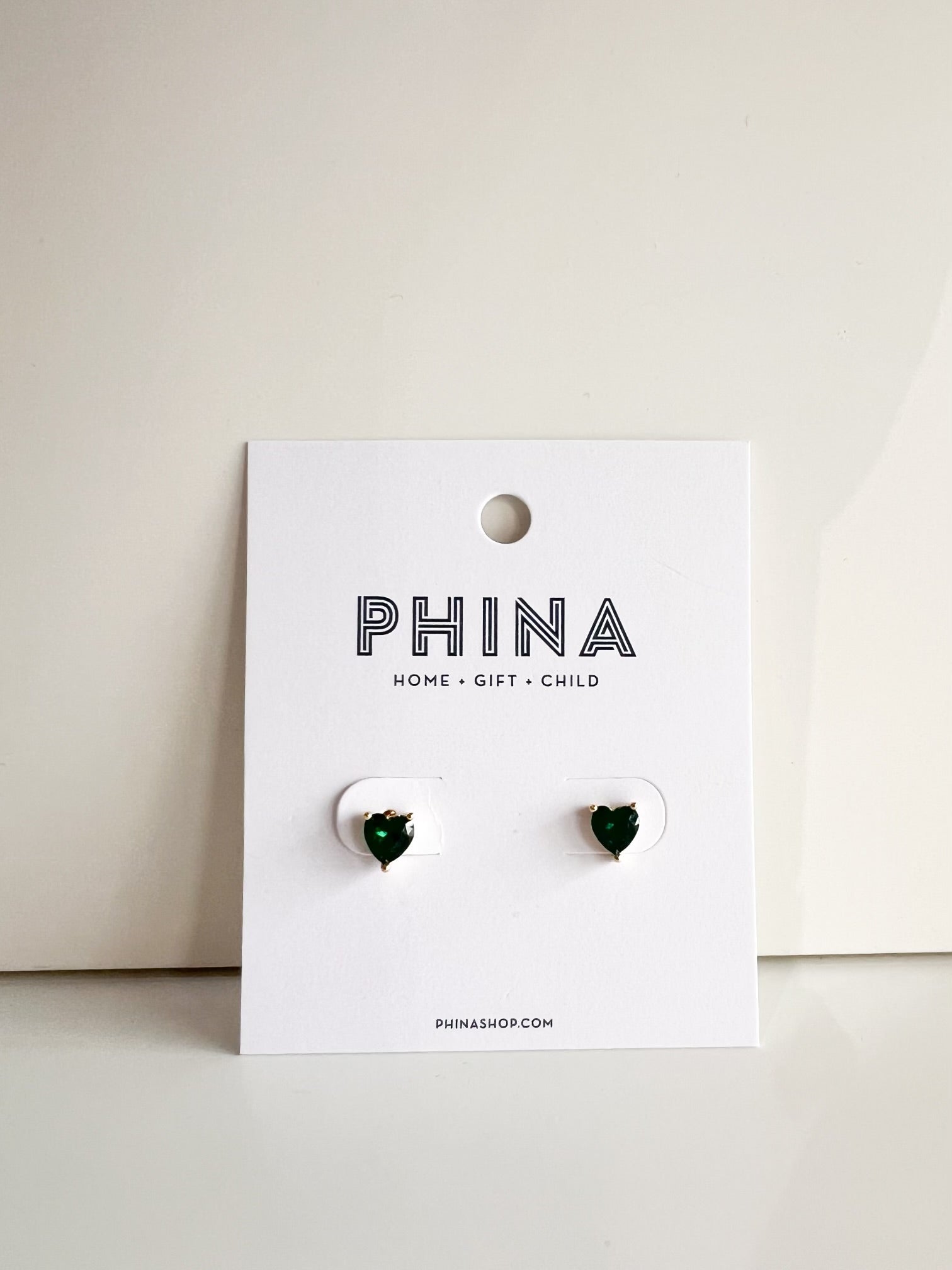 Green heart shaped stud earrings on a Phina branded display card