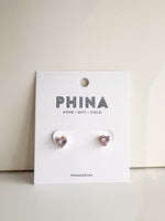 Pair of light purple heart shaped stud earrings on a white display card
