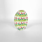A glossy decorative oval object in a studio setting, adorned with wide green horizontal stripes and vibrant pink floral vine patterns with green leaves, bearing a faint LINN inscription