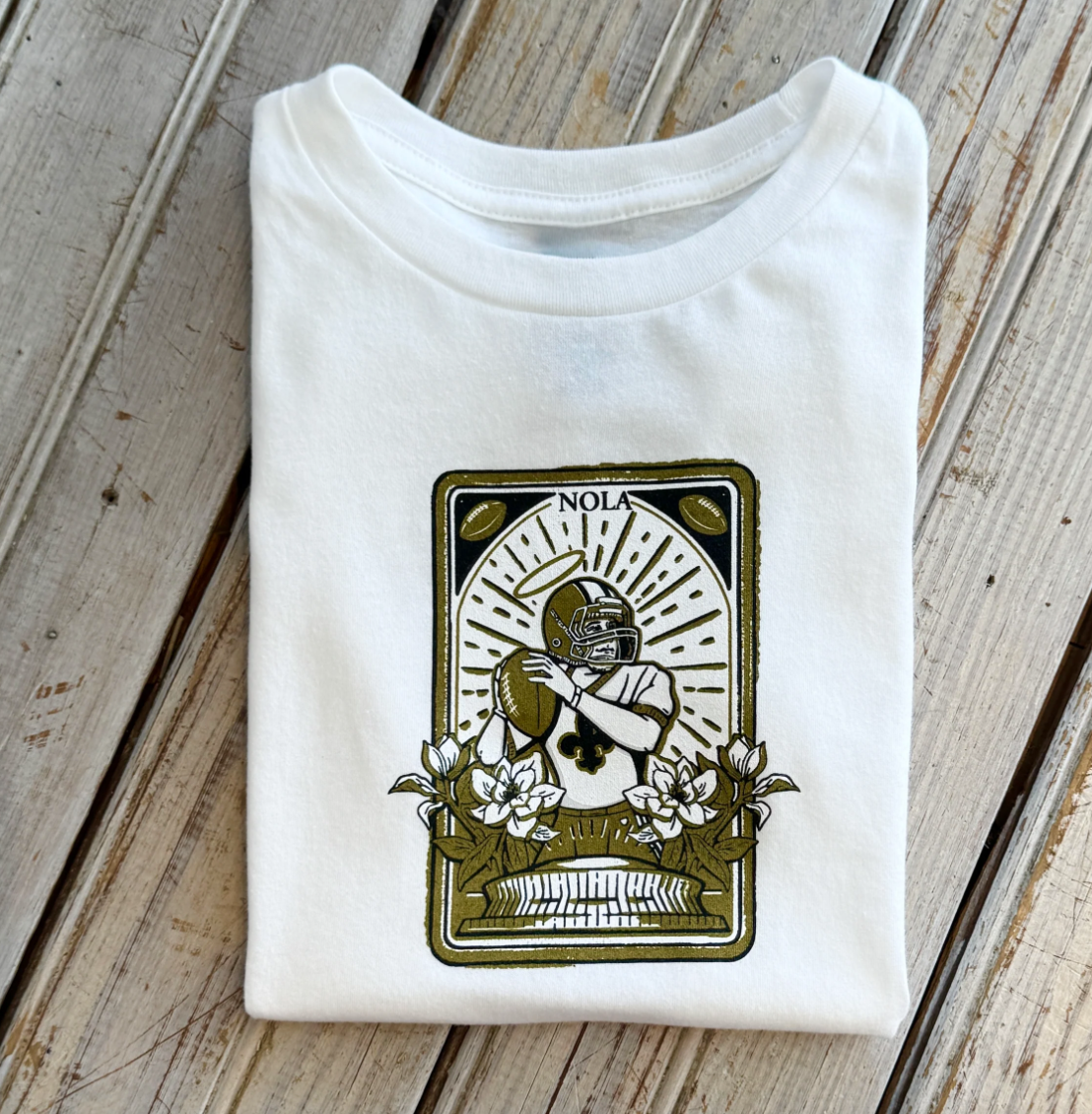 White t-shirt with a NOLA football player graphic featuring a halo and magnolia flowers