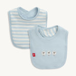 Two baby fabric bibs, one with light blue and white horizontal stripes, the other solid light blue featuring three embroidered white sheep and a small red tag with a white m logo