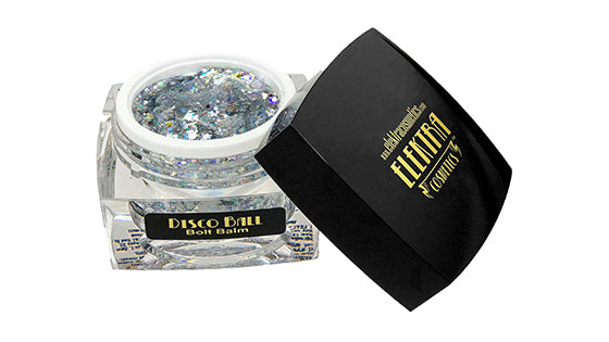 An open clear jar of Elektra Cosmetics Disco Ball Bolt Balm glitter with chunky iridescent silver flakes next to its black lid displaying prominent gold Elektra Cosmetics lettering