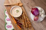 Bowl of creamy dip with seed crackers carrots and onions on a wooden board