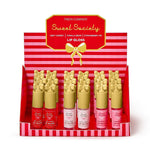 Sweet Society lip gloss display by Two's Company showing rows of Very Cherry, Vanilla Bean, and Strawberry Pie flavors in bottles with distinctive gold bow-shaped caps on a red and white striped stand