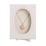 Gold-toned heart locket necklace featuring a pink enamel bow with a small clear gemstone displayed in a white gift box with a scalloped pink border and pink polka dot backing