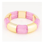 Gold-tone metal and resin stretch bracelet on a white background featuring alternating polished metallic segments and translucent pink marbled blocks