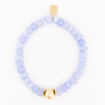Beaded bracelet with light blue faceted chalcedony beads a textured gold central bead and a small rectangular gold charm with an engraved pattern
