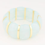 A pale blue translucent segmented bracelet with vertical gold-tone bar spacers on a white background