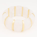 White translucent resin and gold-toned metal bangle bracelet with thick segmented design on a plain white background