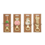 Four metal bottle openers shaped like a champagne bottle, engagement ring, wedding cake, and the word cheers