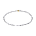 Delicate beaded stretch bracelet with tiny sterling silver beads and one central polished gold bead on a white studio background