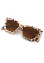 A close-up photograph of a pair of multi-color confetti pattern sunglasses with brown lenses and distinctive scalloped frame edges