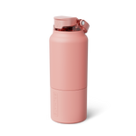Matte blush pink BRÜMATE water bottle on a white background featuring a flip-top lid with a clear amber spout and integrated carrying loop, with the brand name embossed vertically on its lower body