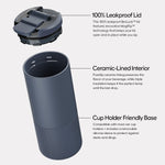 Product rendering of a dark grey BrüMate BevLock travel mug disassembled on a light background, highlighting its 100% leakproof MagFlip lid, ceramic-lined interior, and cup holder friendly base with a protective silicone sleeve, all detailed by descriptive text