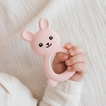 Baby hand holding a pink silicone rabbit shaped teether
