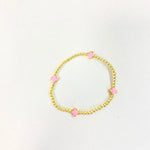 Gold beaded stretch bracelet featuring four spaced pink enamel clover charms on a white background