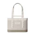 Product photograph of a Yeti Camino Carryall tote bag in cream featuring a reinforced tan base, an embossed central logo, and durable shoulder straps with integrated utility loops against a black background