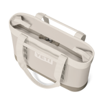 Product photograph of a YETI Camino Carryall tote bag on a black background featuring a cream-colored waterproof shell, the prominent white YETI logo, and a zippered top closure with reinforced straps and utility loops