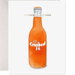 Watercolor illustration on greeting card featuring a vibrant orange soda bottle with a silver cap and a white 'Crushed It' label with an orange slice icon beneath gold 'CONGRATULATIONS' text